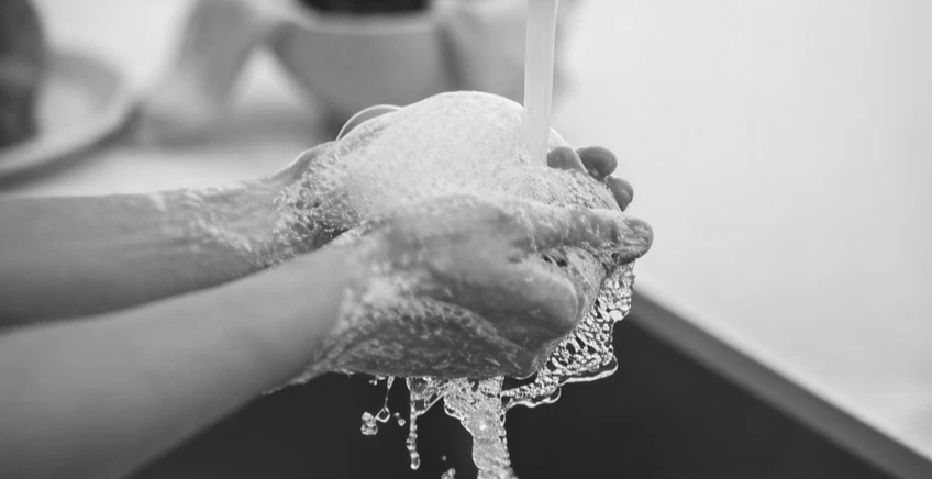 People washing hands with soap under running water, creating lather and bubbles