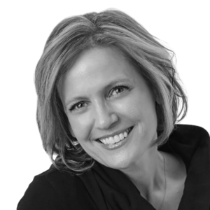 Smiling woman with short blonde hair, wearing a dark top, facing slightly to the right (black-and-white portrait).