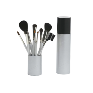 Assorted makeup brushes in a white holder next to a tall cylindrical bottle against a black background.